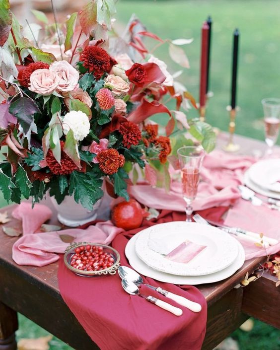 a bright fall wedding table with pink and marsala runners, a colorful floral centerpiece with marsala and blush blooms, marsala and black candles
