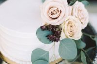 a buttercream-frosted wedding cake with roses and greenery is a very elegant and chic idea