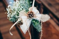 a chair posie of evergreens, a lace and burlap bow, a pinecone, baby’s breath and some twine for a winter wedding aisle