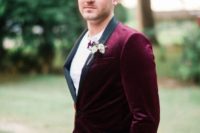 a chic groom’s look with a burgundy tux with black lapels and black pants calmed down with a white tee