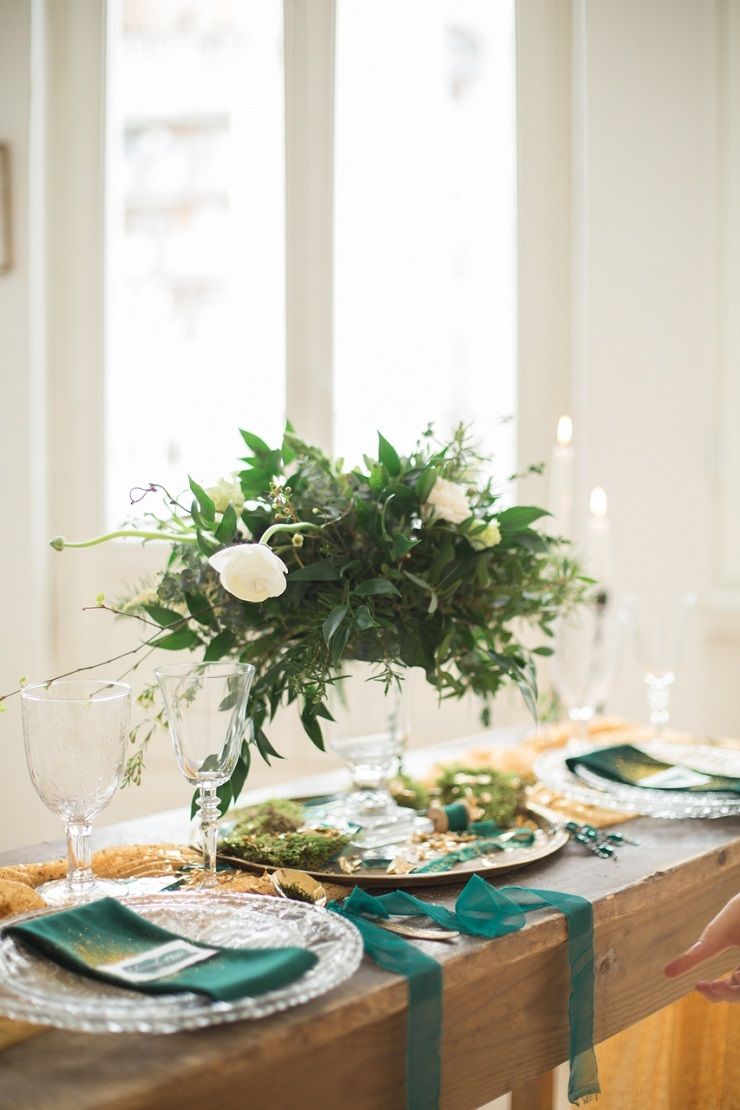 a chic wedding tablescape with navy napkins and ribbons, a greenery and white bloom centerpiece, moss and a gold table runner