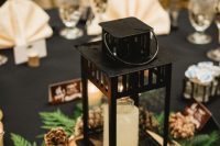 a cozy winter wedding centerpiece of a wood slice, a candle lantern, evergreens and pinecones is amazing