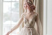 a fairy tale blush A-line wedding dress with floral appliques, long sleeves, a deep neckline and a matching headpiece