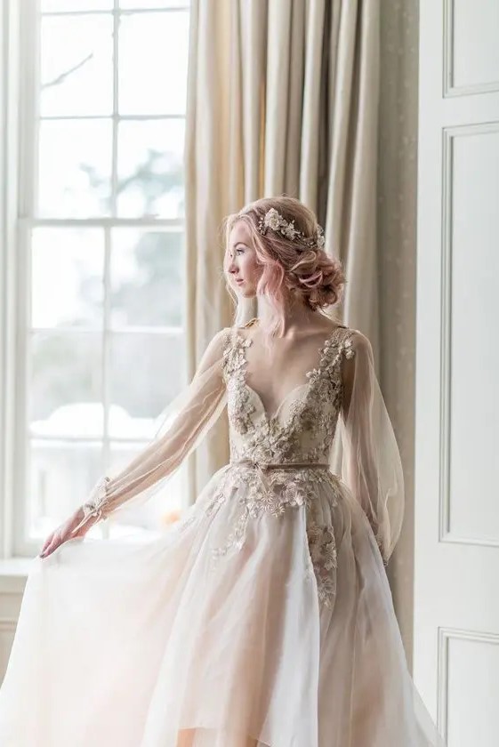 a fairy tale blush A-line wedding dress with floral appliques, long sleeves, a deep neckline and a matching headpiece