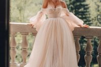 a faiytale blush off the shoulder wedding dress with puff sleeves, a draped bodice and a layered tulle skirt with a train