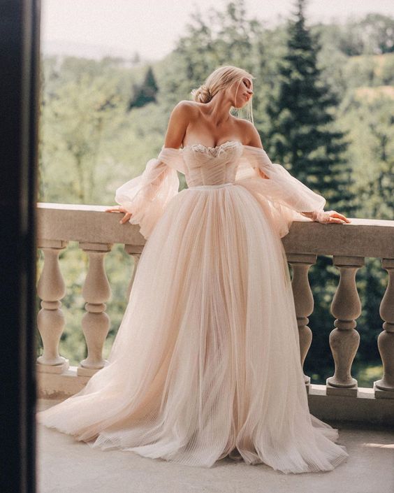 a faiytale blush off the shoulder wedding dress with puff sleeves, a draped bodice and a layered tulle skirt with a train