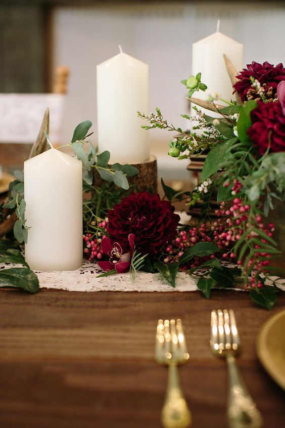 a lovely wedding tablescape with marsala blooms, berries, candles on tree stumps, greenery and gold touches
