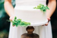 a minimal white buttercream one tier wedding cake with fresh greenery is a very stylish idea for a modern wedding