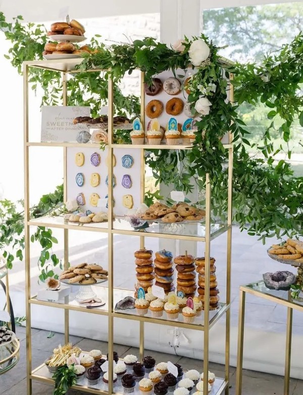 a modern wedding dessert shelf with colorful geodes, lots of greenery, white blooms and signs is all cool