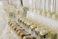 a modern white wedding dessert table with ladders as stands, white blooms is a very sophisticated and chic idea
