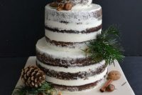 a naked winter wedding cake with nuts, cinnamon sticks, evergreens and pinecones looks amazing
