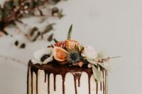 a one tier buuttercream wedding cake with chocolate drip, fresh blooms, greenery and figs on top