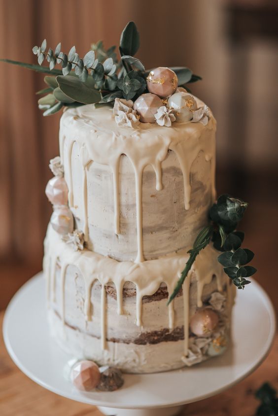 a semi naked cake with creamy drip, fresh eucalyptus and geo candies is a cool idea for a winter bridal shower