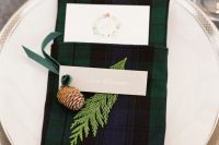 a tartan napkin pocket with a pinecone and fern is a stylish idea to decorate your wedding tablescape