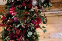 a wedding arch with red, marsala and pink blooms, greenery, foliage and neutral blooms is a lovely idea to rock