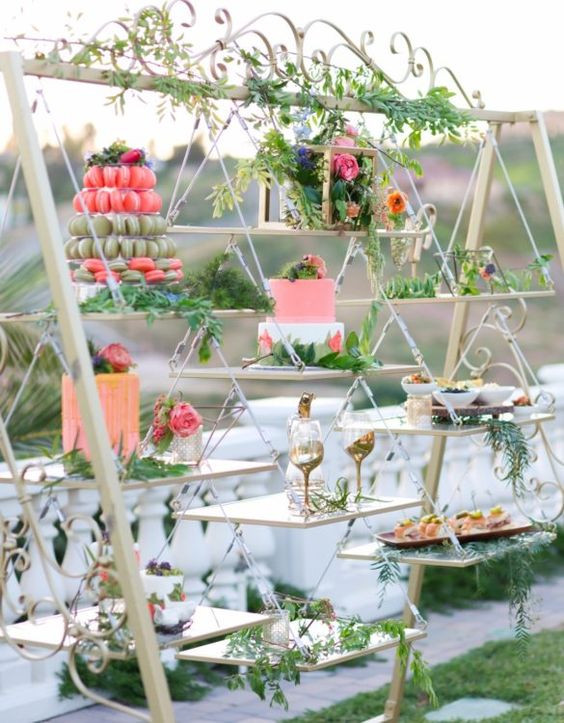 a wedding dessert swing decorated with greenery and bright blooms is a lovely alternative to a usual wedding dessert table