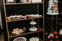 an elegant arched brass shelving unit with photos and lots of desserts, candles and blooms is a stylish idea for a modern wedding