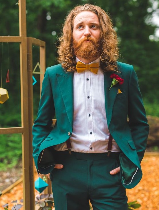 an emerald suit, a white shirt with black buttons, suspenders and a mustard bow tie to pull off a jewel color palette