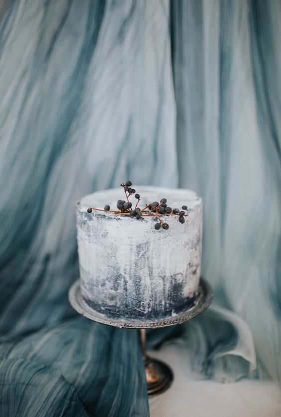 an ombre textural one tier wedding cake with touches of blue and some berries on top is a very chic idea for a winter wedding