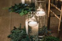 evergreen and greenery arrangements with floating candles in tall vases are nice to accent your wedding aisle