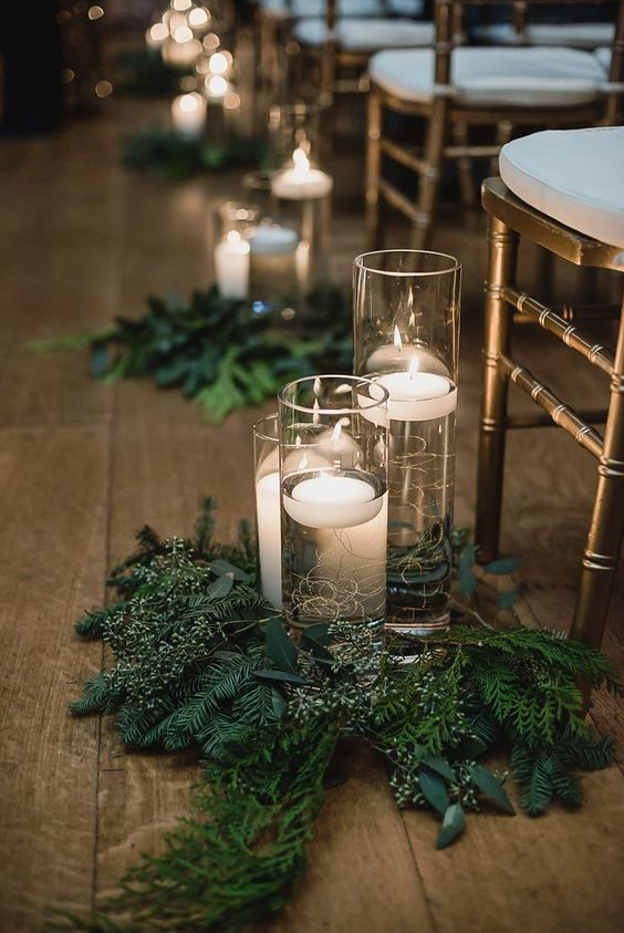 evergreen and greenery arrangements with floating candles in tall vases are nice to accent your wedding aisle