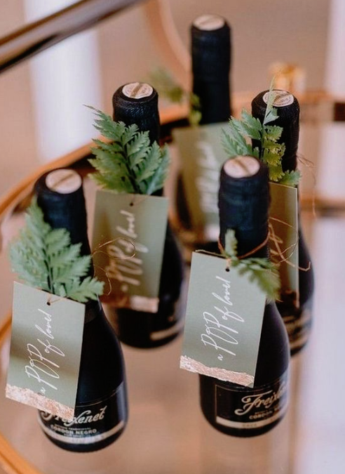mini alcohol bottles topped with cards and evergreens will be nice and cool winter bridal shower favors