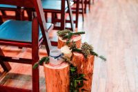 tree stumps with evergreens and cascading greenery and candle lanterns in jars make the aisle very natural and cool