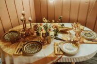 The wedding tablescape was done with a printed tablecloth, bold plates and amber glasses, candles in wooden candleholders and bold blooms