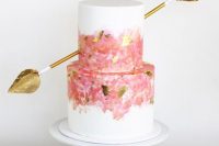 a Valentine wedding cake with pink and gold leaf decor, with an oversized gold arrow is bold and cool