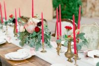a beautiful Valentine’s Day wedding tablescape with white linens, pink candles, greenery, printed and white plates is elegant