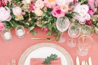 a beautiful Valentine’s day wedding table in pink, with pink linens, bold pink blooms and white candles, gold rimmed glasses and gold cutlery