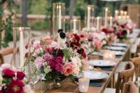 a beautiful and very romantic Valentine’s Day wedding table with bold pink and burgundy blooms, candles, grey plates, navy and gold cutlery