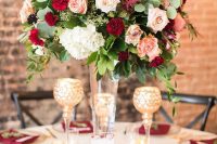 a beautiful floral centerpiece of burgundy, red, blush and white blooms and some greenery looks very chic