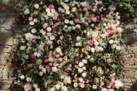 a beautiful lush floral wall with pink, blush and ivory blooms and textural greenery looks very lively
