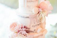 a beautiful naked wedding cake with blush drip, blush blooms and white macarons is a pretty and chic idea