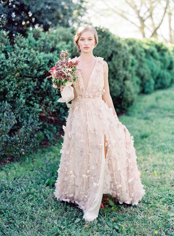 a blush A-line wedding dress with floral appliques and plunging neckline plus a front slit for a romantic bride