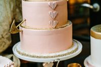 a blush wedding cake decorated with gold glitter and a gold arrow for a Valentine wedding with a soft color scheme