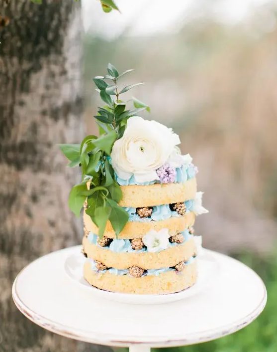 a boho naked wedding cake with blue cream, gilded blackberries, a large blooms and foliage is amazing for spring or summer