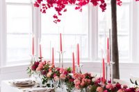 a bold Valentine’s Day wedding table with lots of bold blooms, pink candles, a pink tree, gold cutlery and white porcelain
