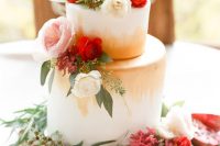 a bold modern Valentine wedding cake with gold touches, pink, red and white blooms, greenery and berries is a lovely idea