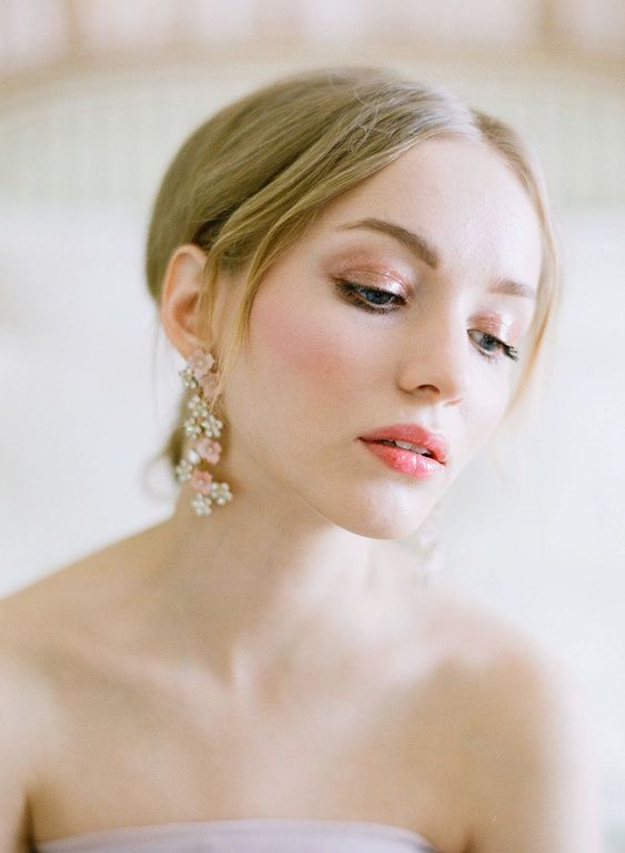 a bright spring wedding makeup with a bright pink glossy lip, peachy eyeshadow, a touch of pink blush, accented eyebrows