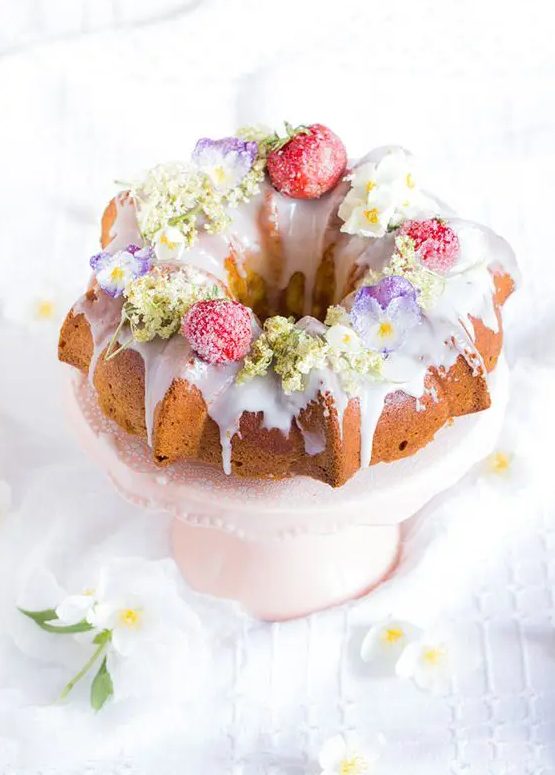 a bundt cake with creamy drip, sugared and dried blooms and berries on top is a lovely idea for a boho wedding