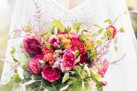 a colorful Valentine wedding bouquet of fuchsia and orange blooms, much greenery and foliage looks chic and elegant