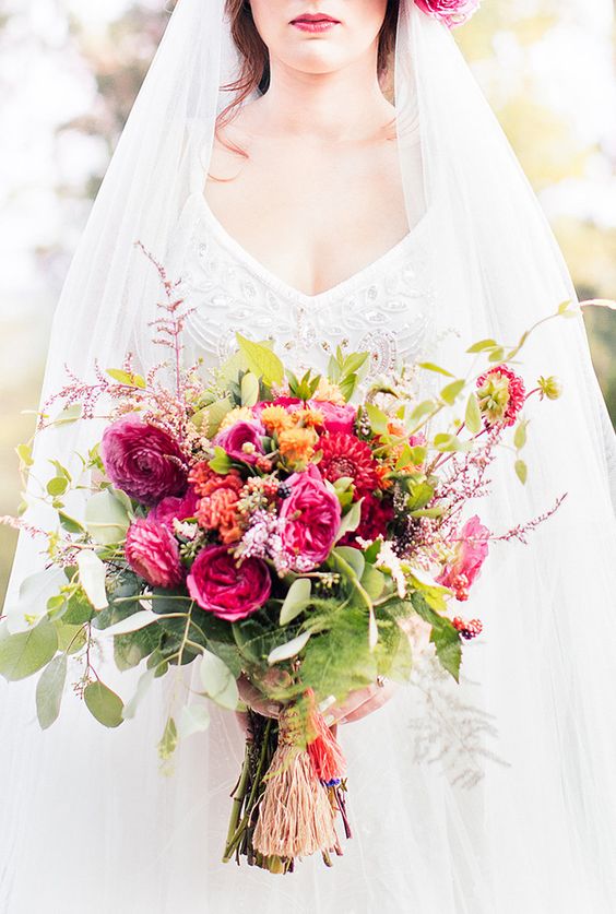 a colorful Valentine wedding bouquet of fuchsia and orange blooms, much greenery and foliage looks chic and elegant