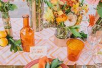 a colorful summer wedding tablescape with a printed table runner, bright blooms, glasses and neon cutlery, colorful plates