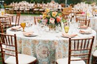 a cool and catchy wedding tablescape with a printed tablecloth, bold blooms and greenery, amber glasses for a summer celebration
