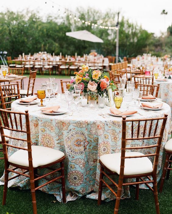 a cool and catchy wedding tablescape with a printed tablecloth, bold blooms and greenery, amber glasses for a summer celebration