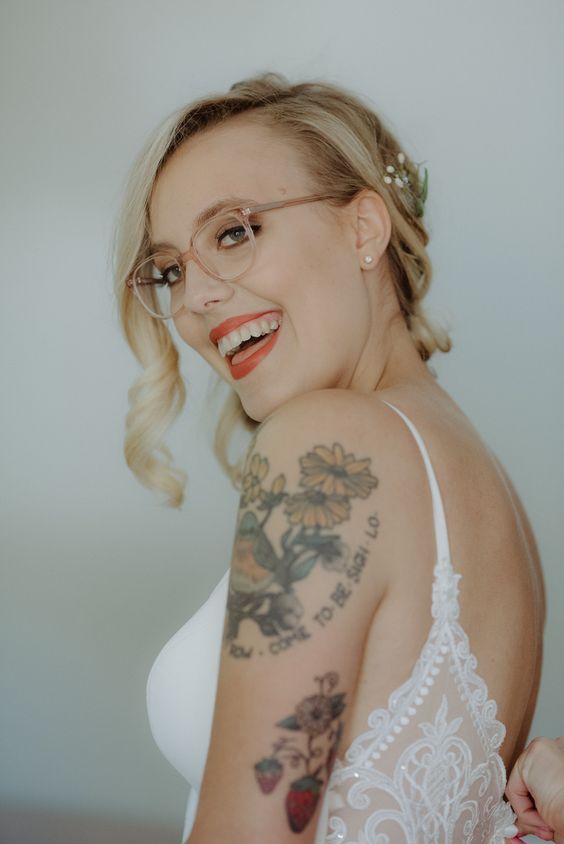 a cool bold wedding makeup with a red lip, a bit of brown eyeshadow, eyeliner and mascara and a clear eyeglasses frame