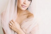 a delicate neutral wedding makeup with a shiny blush lip, mauve eyeshadow, a touch of blush on the cheeks and perfect skin