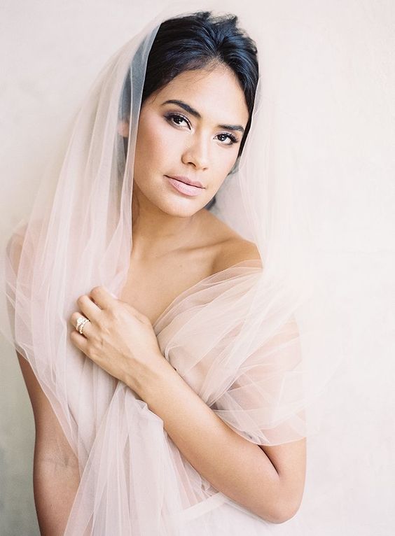 a delicate neutral wedding makeup with a shiny blush lip, mauve eyeshadow, a touch of blush on the cheeks and perfect skin